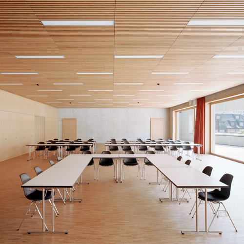 Holzdecke in der Aula einer Schule. Realisiert durch Röösli Funktionsdecken.